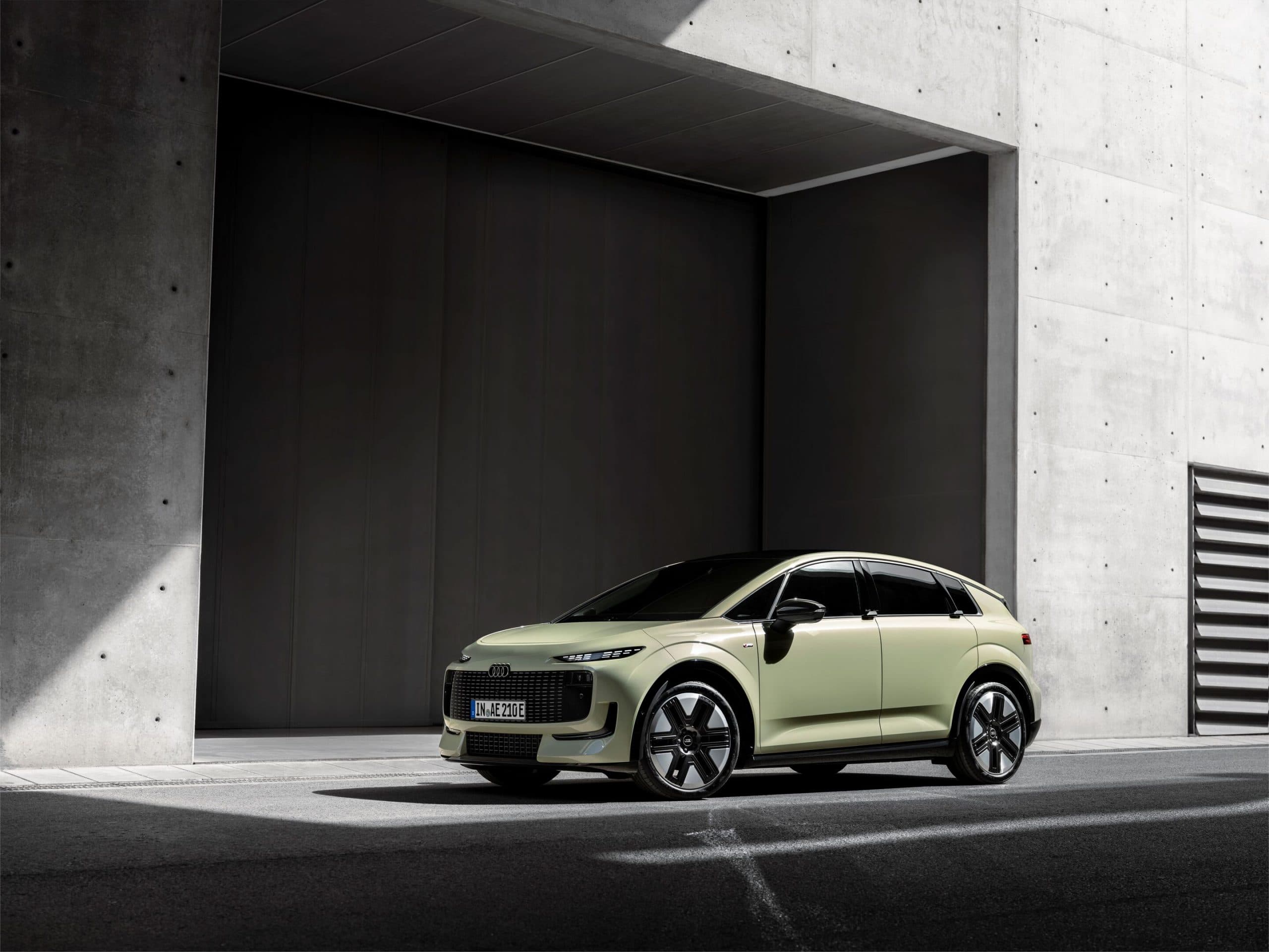 Pale green Audi A2 e-tron compact electric hatchback, front three-quarter view, German IN AE 210 E plates, parked in front of a concrete building