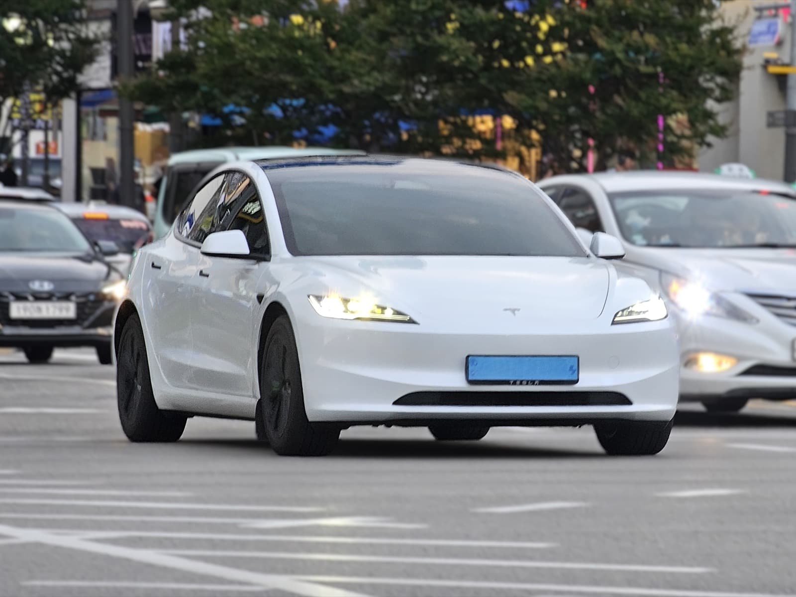 Pearl white Tesla Model 3 Highland sedan, front three-quarter view