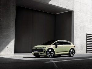 Pale green Audi A2 e-tron compact electric hatchback, front three-quarter view, German IN AE 210 E plates, parked in front of a concrete building