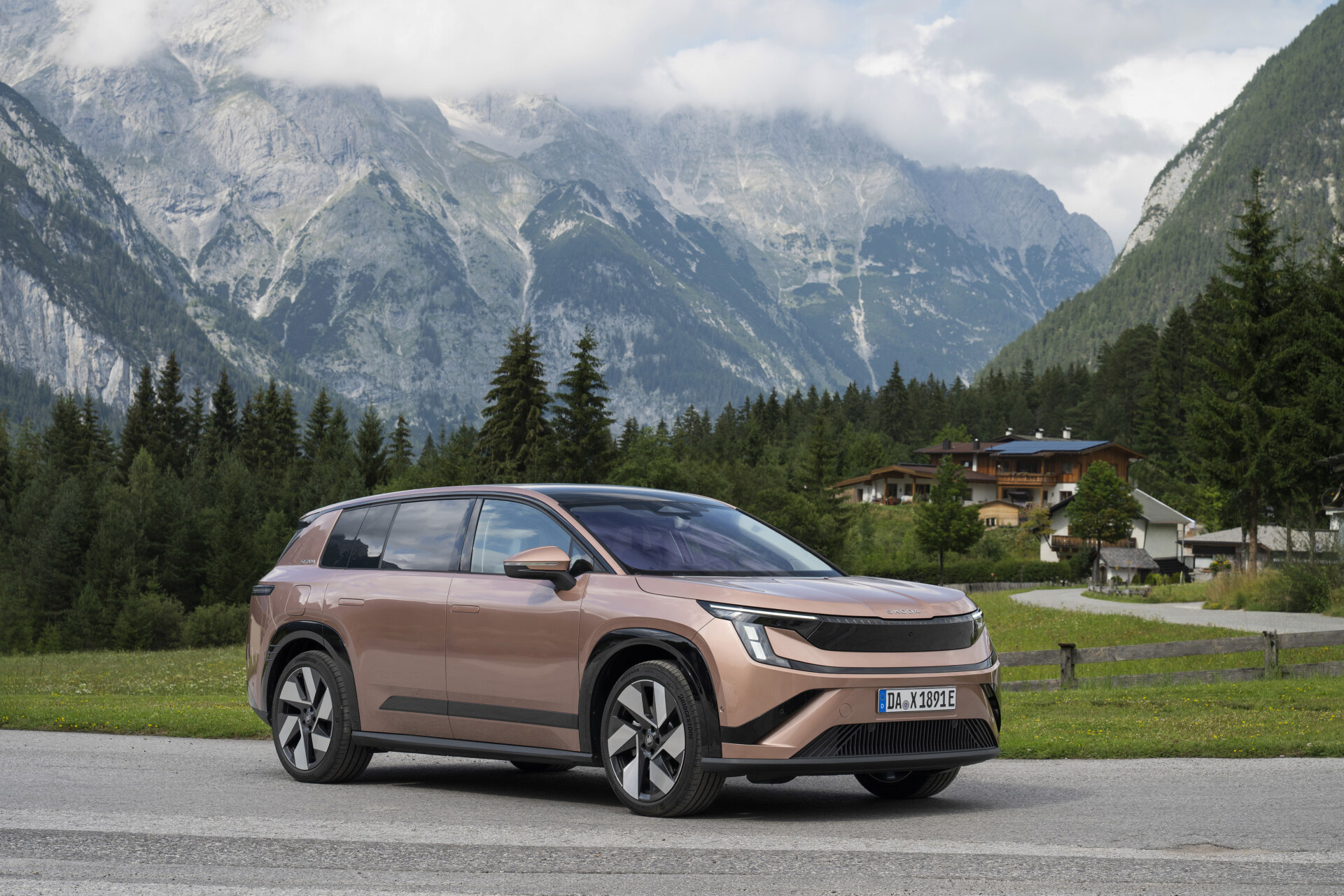 Copper Škoda Peaq battery SUV parked on an alpine roadside, front three-quarter view with mountains behind