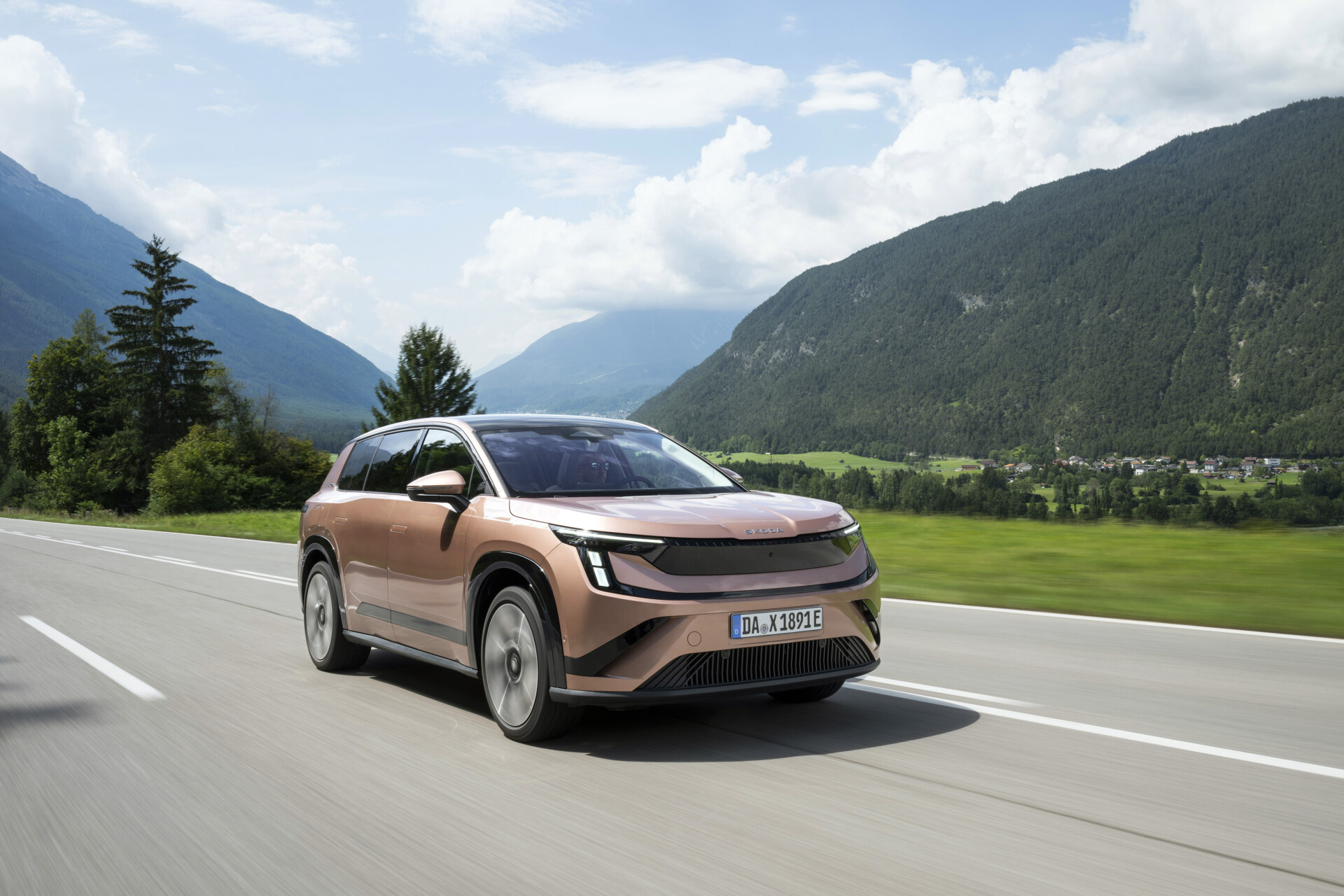 Copper Škoda Peaq battery SUV driving on a valley road, front three-quarter view, German dealer plate DA X 1891 E