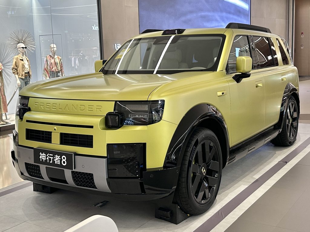 Pale yellow Freelander 8 SUV on a showroom stand, front three-quarter view, FREELANDER lettering across the nose