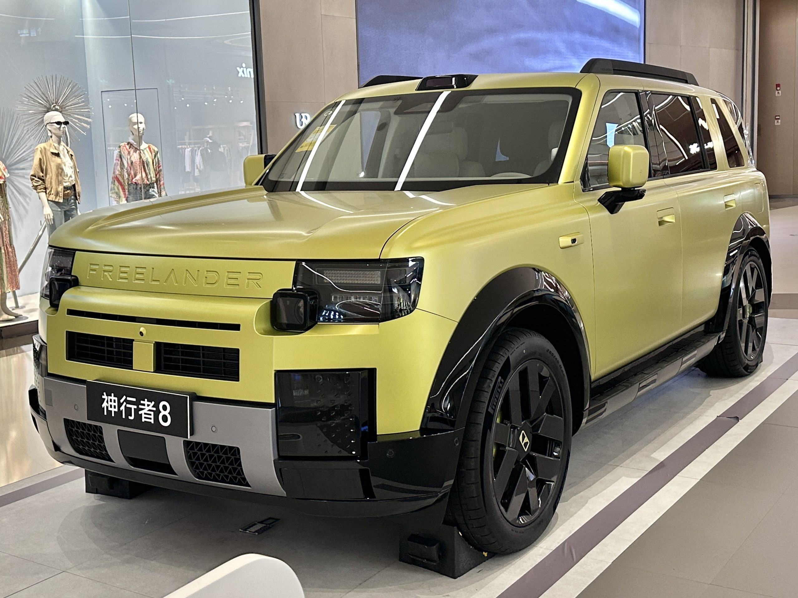 Pale yellow Freelander 8 SUV on a showroom stand, front three-quarter view, FREELANDER lettering across the nose